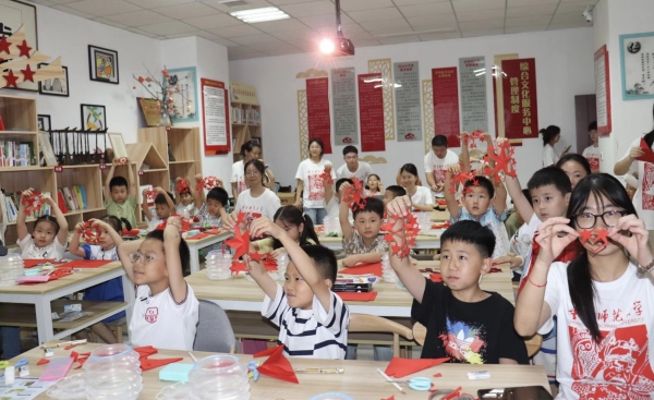 实践团成员与孩子们共同创作剪纸作品。beat365中文官方网站美术学院供图